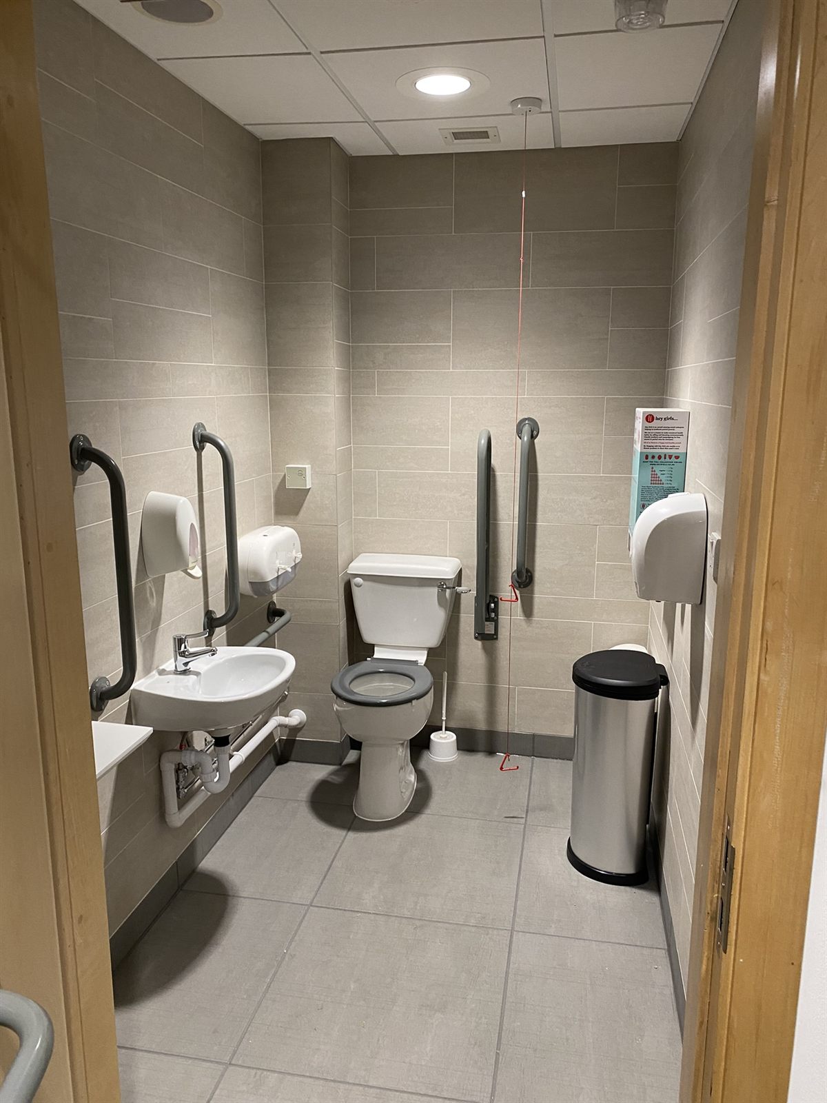 Refurbished accessible WC with grab rails, wall-hung basin and emergency pull cord