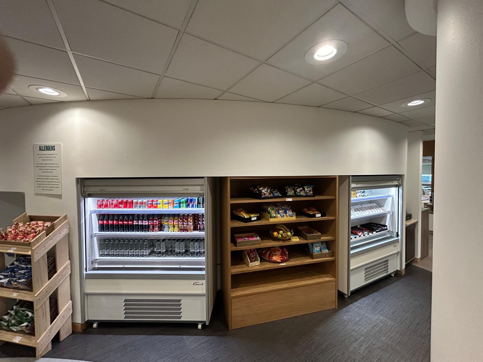 Refrigerated display units flanking bespoke timber shelving in a refreshment area