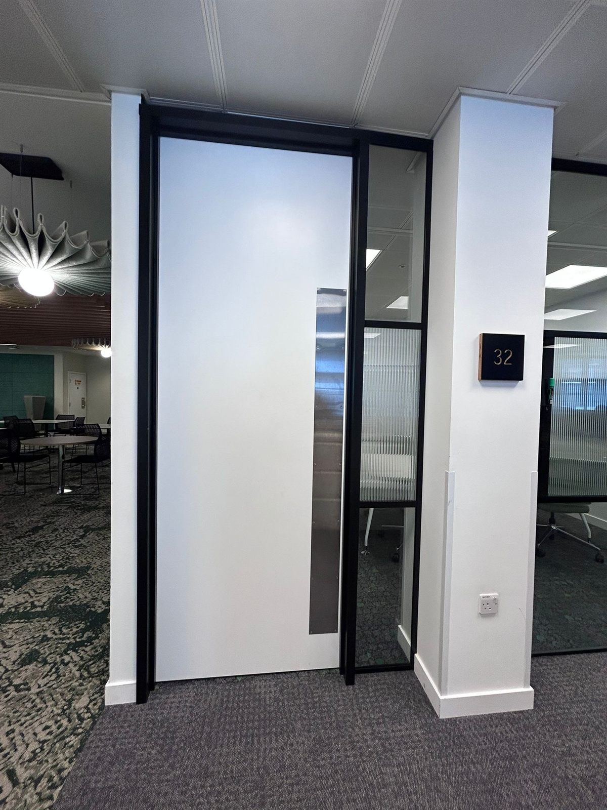 Installed doorset with brushed-steel kick and push plates in an office