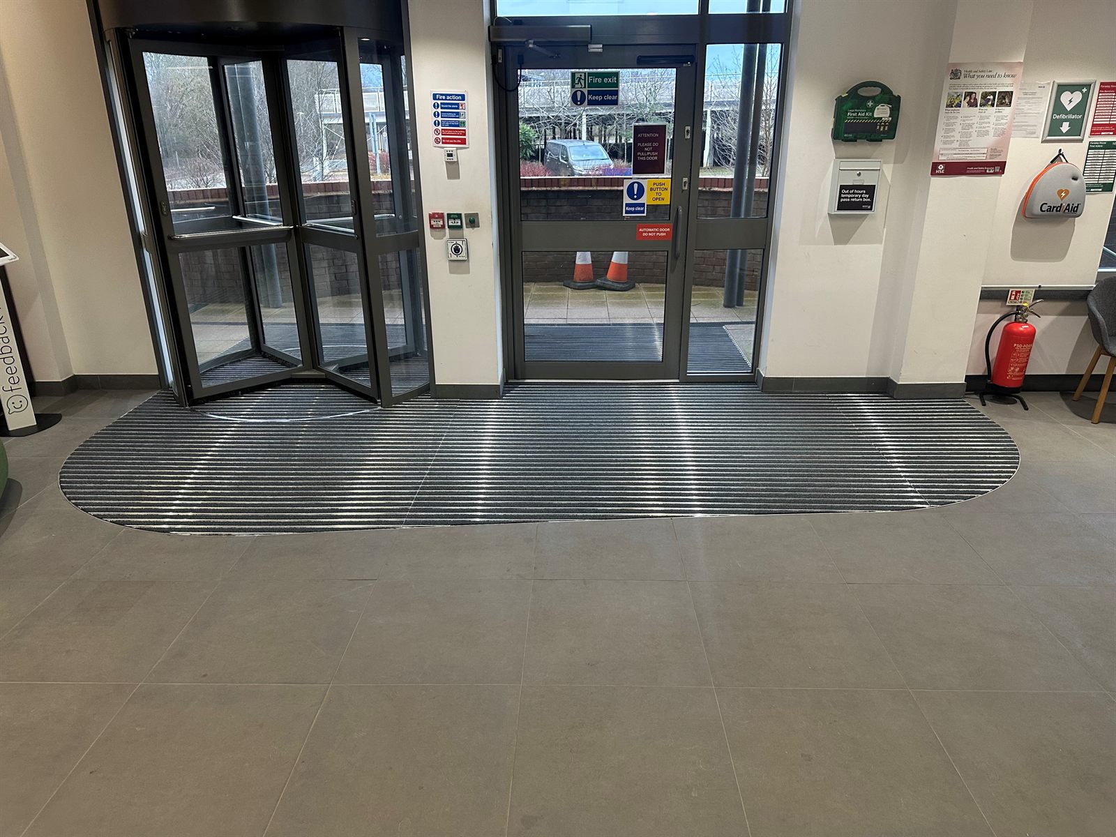Recessed semicircular barrier matting at a revolving-door entrance lobby