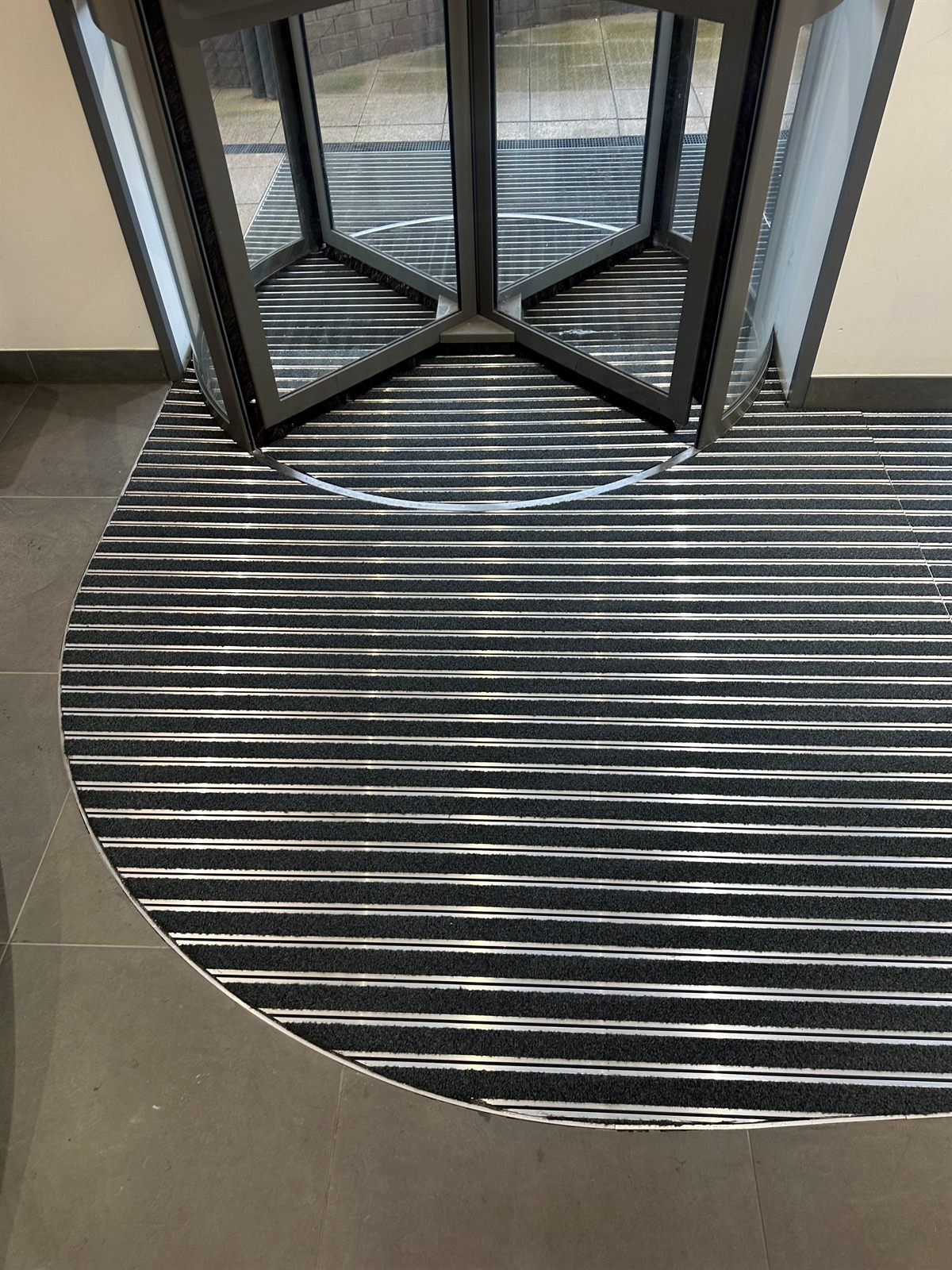 Close-up of recessed striped barrier matting at a revolving door
