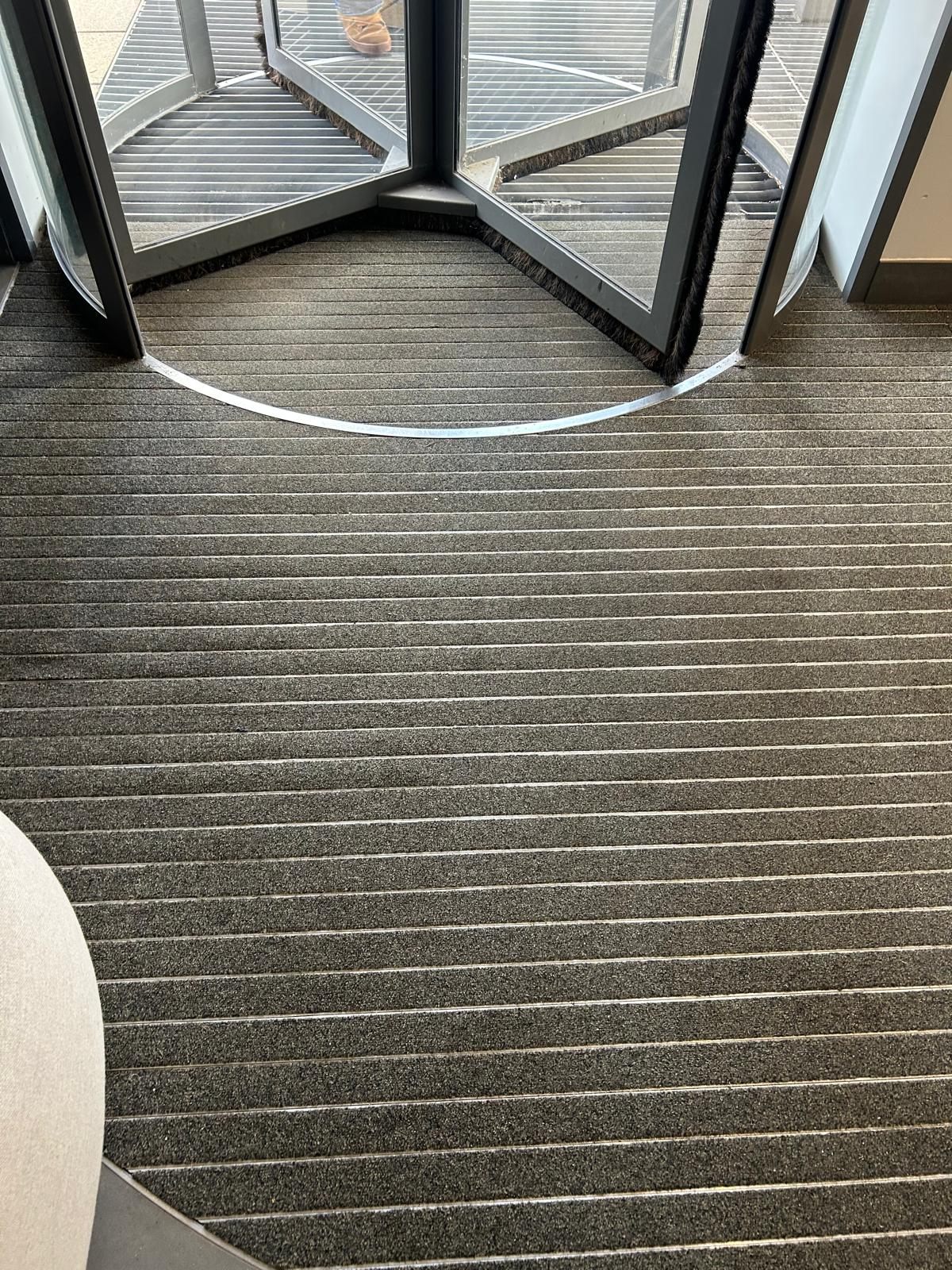 Worn matting at a revolving-door entrance before replacement