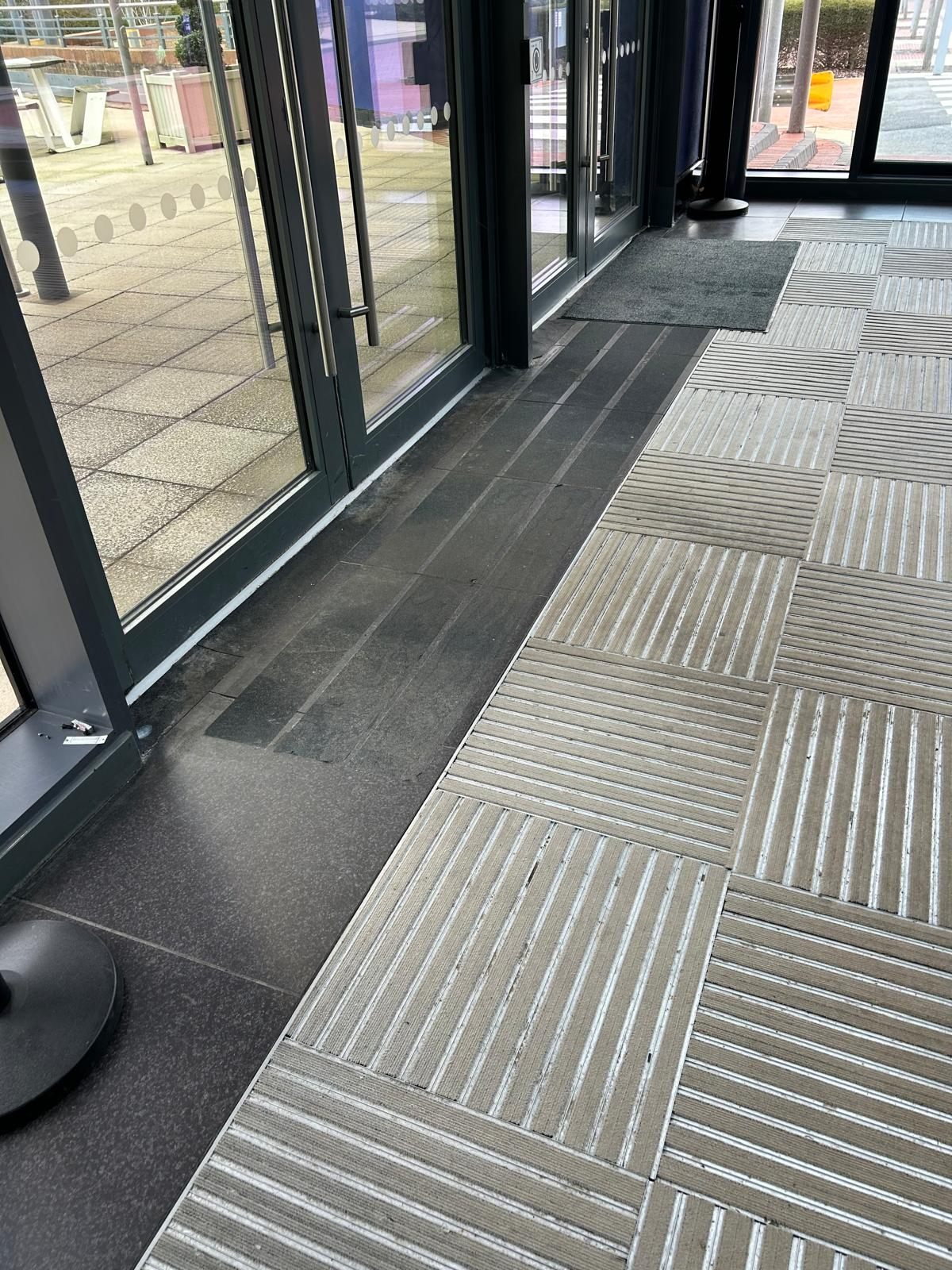Old, worn entrance matting at a second site before replacement