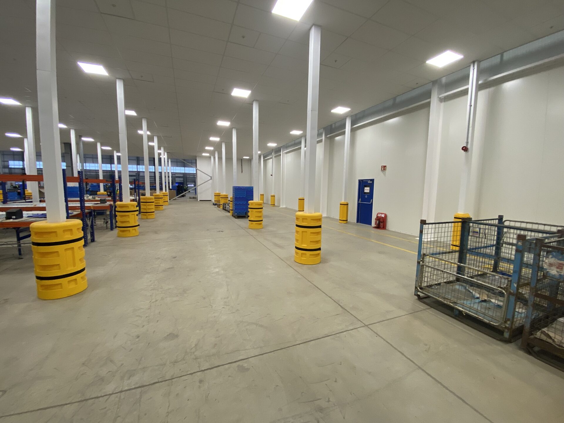 Warehouse aisle before racking installed — column guards and floor marking in place