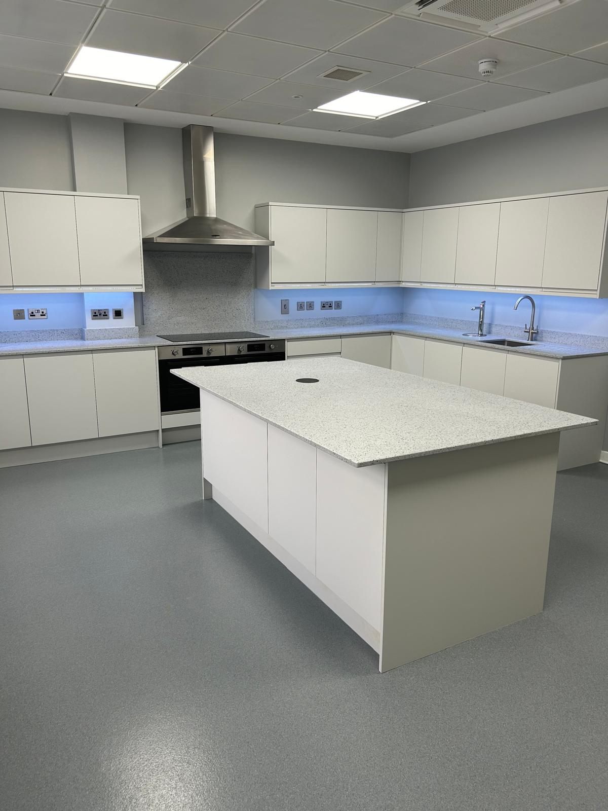 Newly fitted kitchen with central island, induction hob and feature lighting