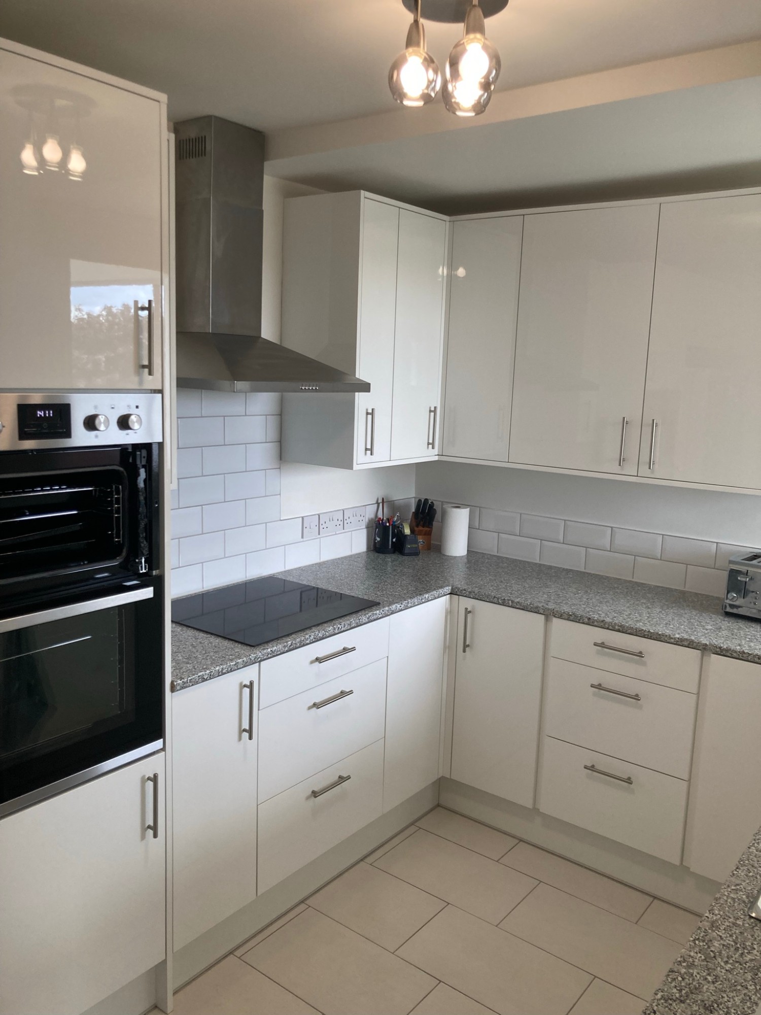 Newly fitted gloss kitchen with granite worktops, integrated oven and tiled splashback