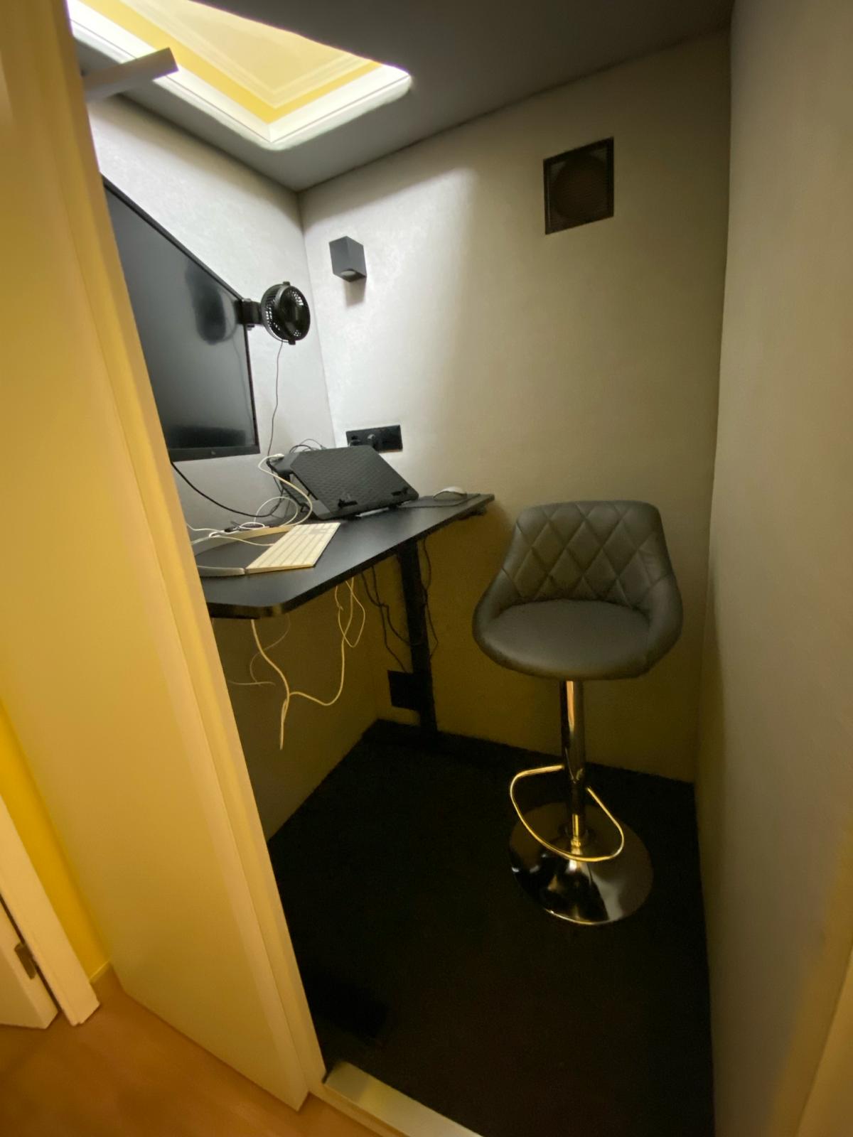 Interior of an acoustic office pod fitted with desk, monitor and stool