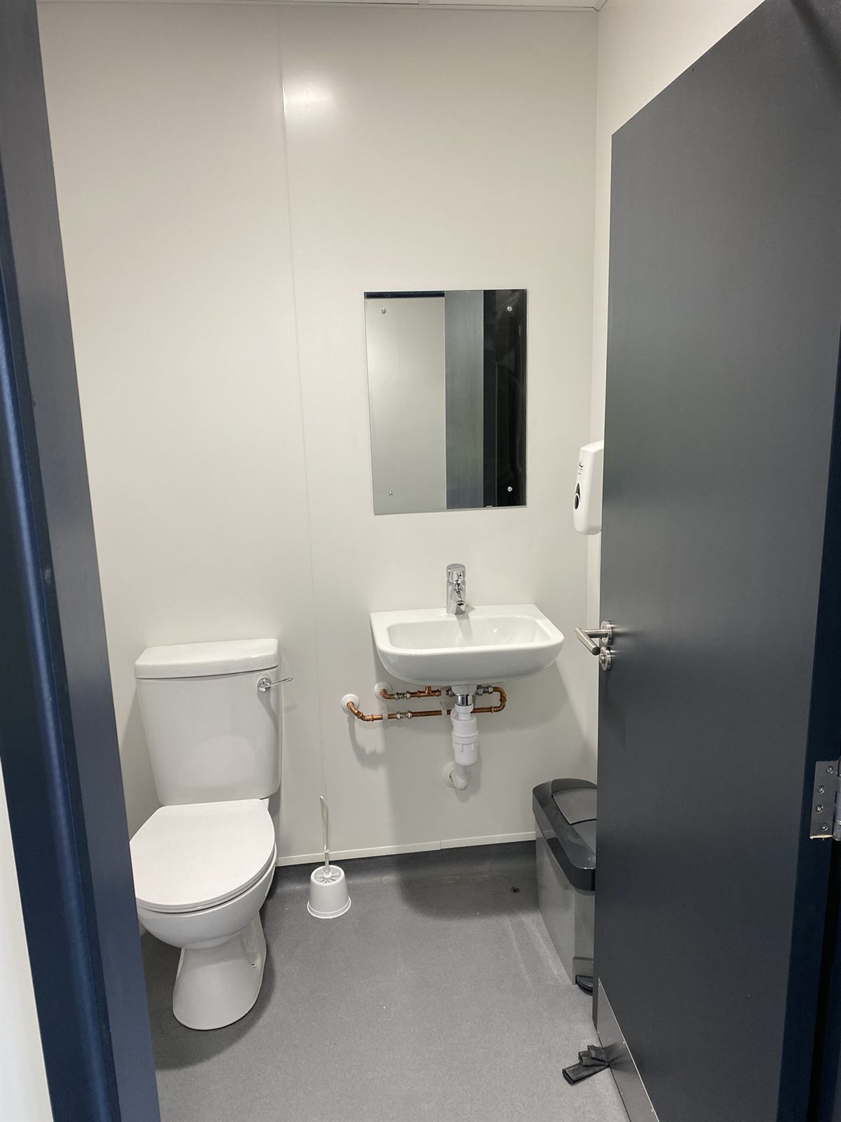 Refurbished WC with hygienic wall cladding and grey resin floor